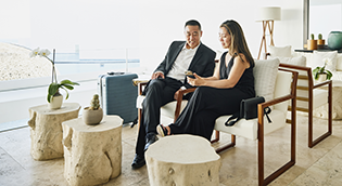 Couple seated in a modern living space reviewing financial information together on a tablet.